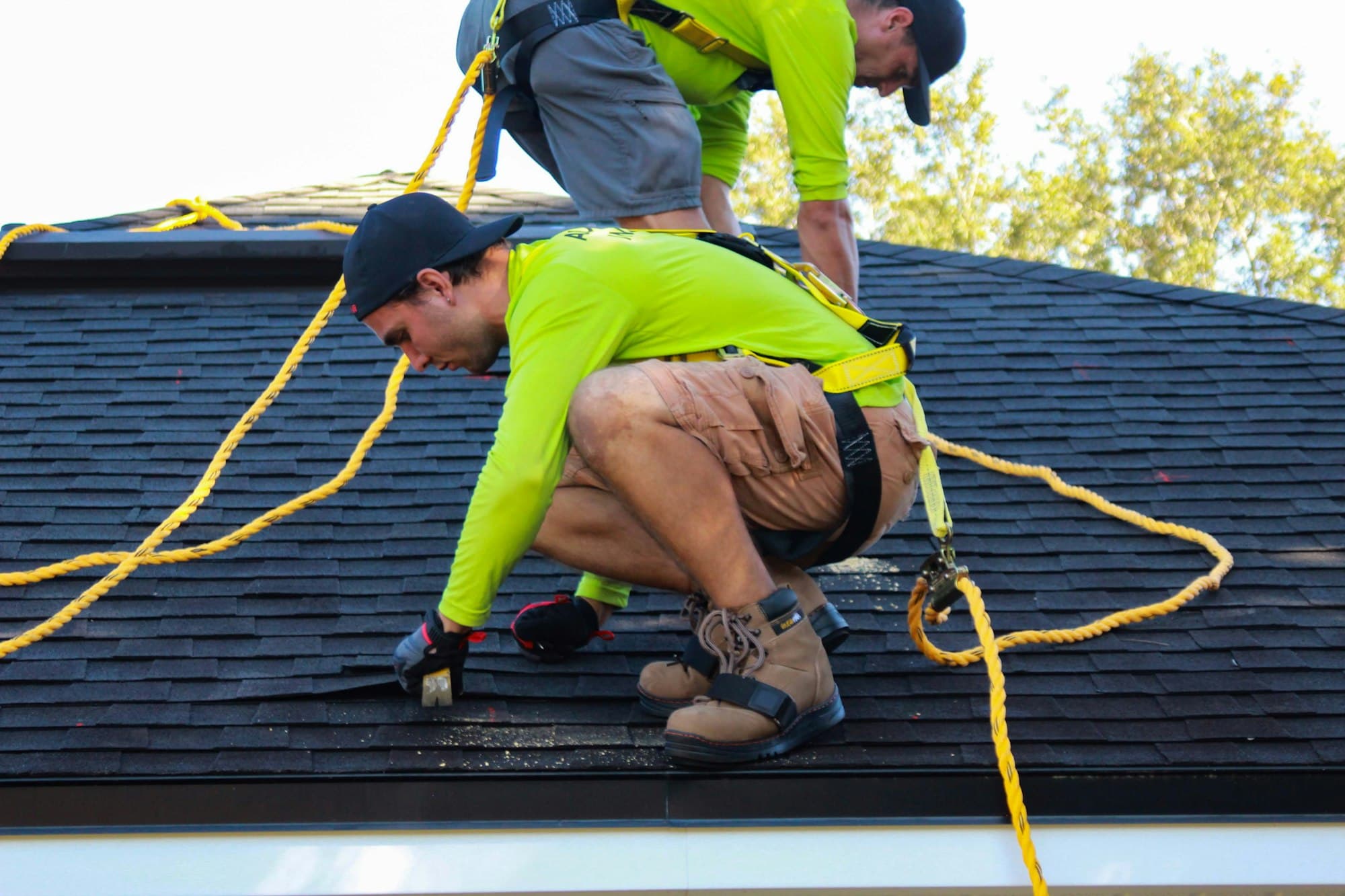 Roofer fastening shingles with a drill