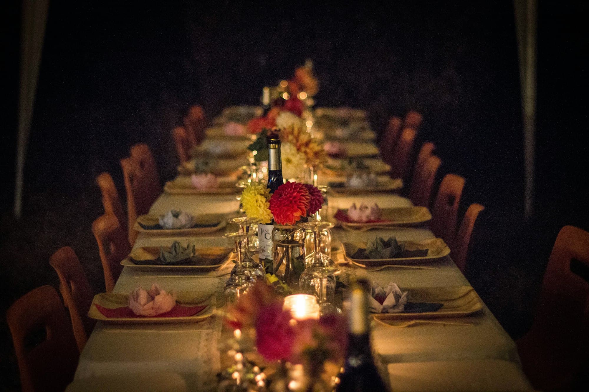 A long dinner table dressed with flowers and candles